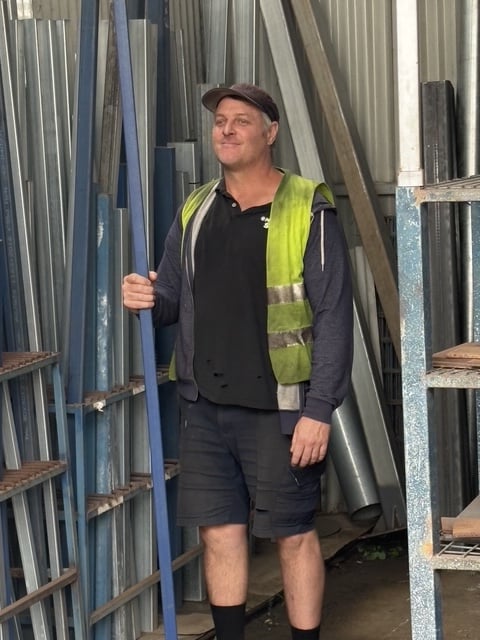 Marshall Steel yard hand in hi-vis, standing between the vertical stock racks