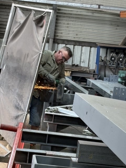 Fabricator grinding a bracket in the Marshall Steel workshop
