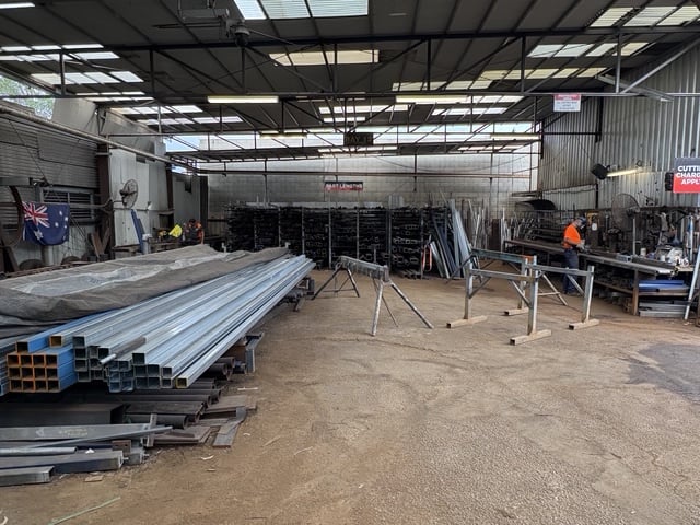 Wide view inside the Marshall Steel workshop — stock racks, benches and workers