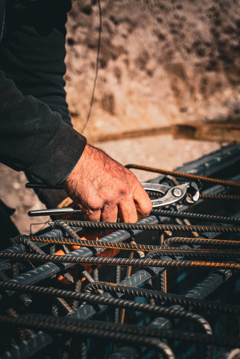 Hands tying reo bar with pliers — reinforcing cage assembly